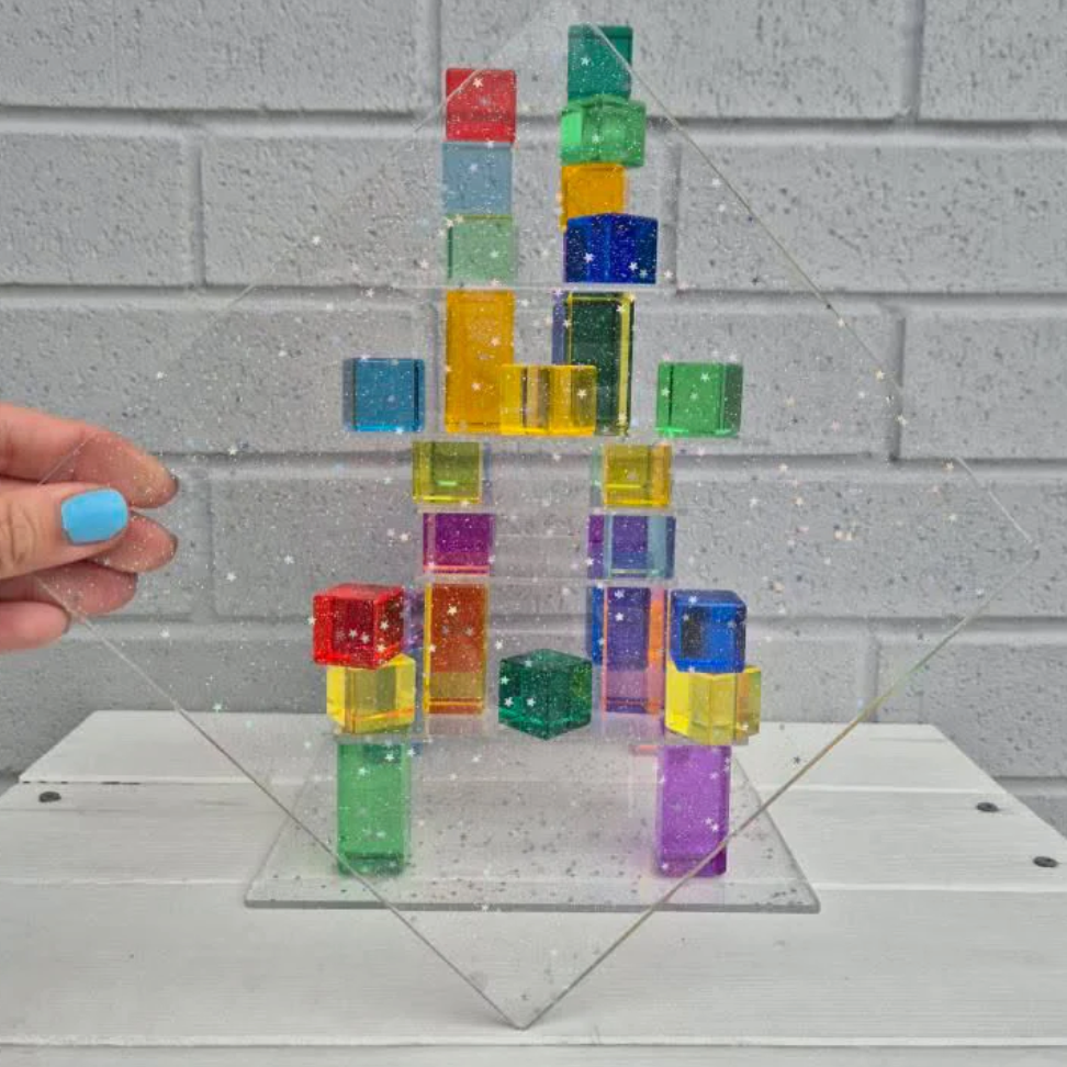Colorful transparent building blocks stacked on a clear base with a hand holding the base.