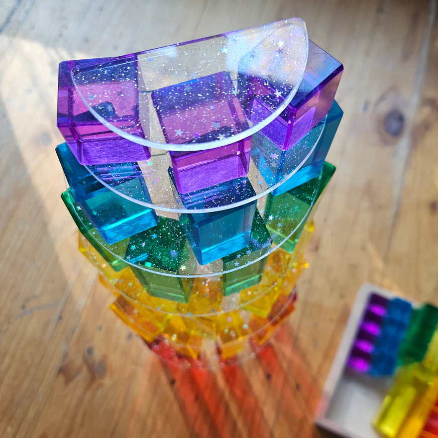 Stack of colorful transparent building blocks on a wooden surface