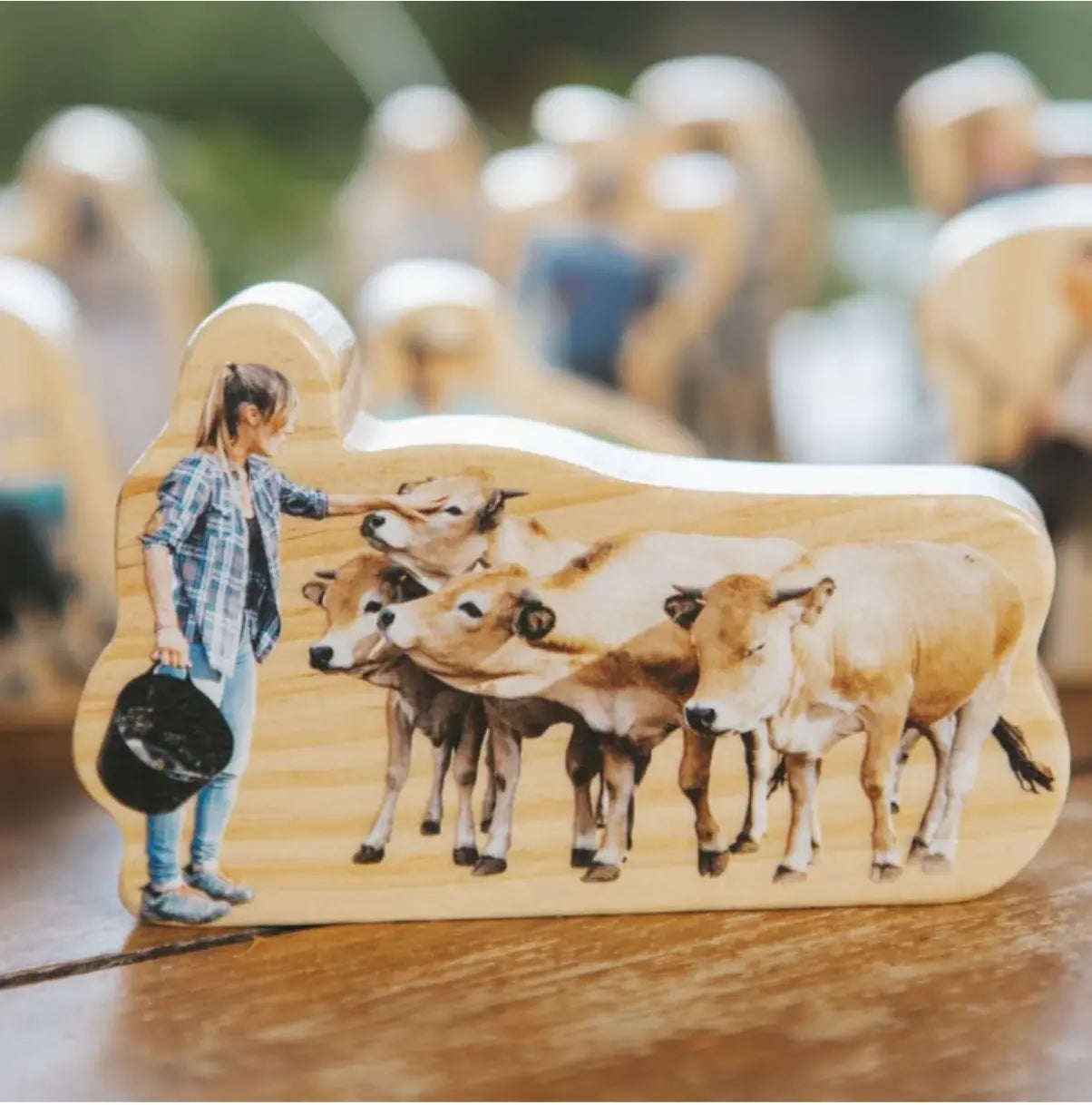 Wooden cutout of a person with cows, placed on a wooden block for role play