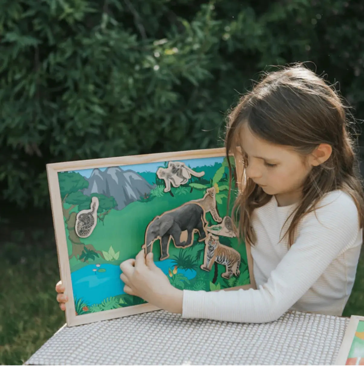 Young girl playing with a wooden animal puzzle outdoors